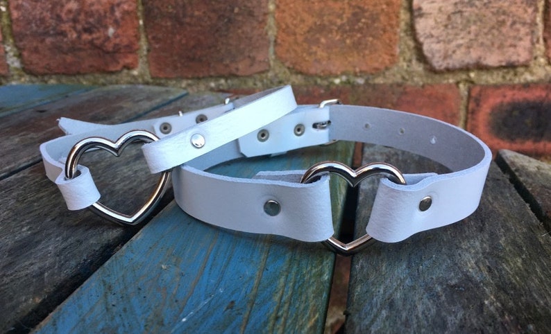 May include: White leather choker with a silver heart-shaped buckle.