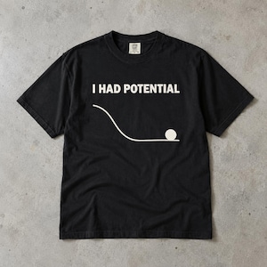 Peut inclure: Un t-shirt noir à manches courtes avec le texte blanc I HAD POTENTIAL imprimé au-dessus d'un graphique représentant une ligne courbe menant à une surface plane avec un petit cercle blanc posé à l'extrémité, illustrant l'énergie potentielle.