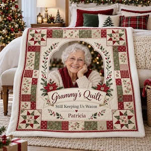 May include: A personalized quilt featuring a central oval photo of an older woman with white hair. The border has a red, green, and cream patchwork star pattern. Text reads: Grammy's Quilt, Still Keeping Us Warm, and the name Patricia.