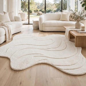 Peut inclure: Un tapis de sol blanc cassé de forme organique irrégulière, doté d'une surface texturée avec des motifs en relief ondulés et fluides qui créent une impression de profondeur et de mouvement sur toute la surface.