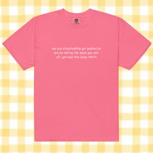 May include: A bright pink short-sleeved t-shirt featuring white text printed on the chest that reads: my dcp situationship got posted on are we dating the same guy and all i got was this lousy tshirt. The garment has a crew neckline.