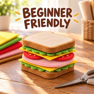 Puede incluir: Un kit de manualidades de fieltro con forma de sándwich que incluye capas de pan beige, lechuga verde, queso amarillo, rodajas de tomate rojo y jamón rosa. El texto BEGINNER FRIENDLY aparece sobre el sándwich junto a unas tijeras.