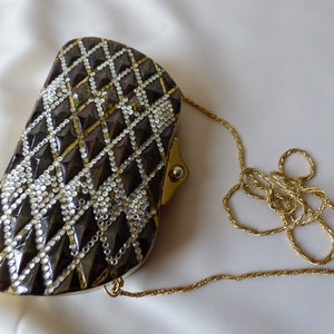 Peut inclure: Un sac de soir&eacute;e noir et or avec un motif en diamant et une bandouli&egrave;re en cha&icirc;ne dor&eacute;e.