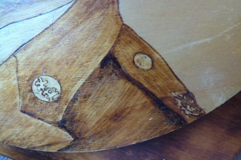 Peut inclure: Gros plan sur une surface en bois avec une teinture brune. La surface pr&eacute;sente deux motifs circulaires br&ucirc;l&eacute;s. Les motifs sont complexes et d&eacute;taill&eacute;s.