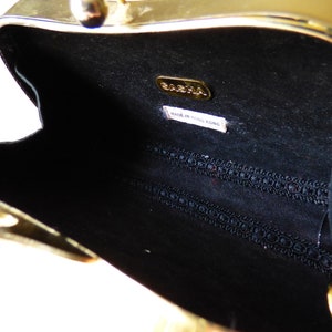 Peut inclure: Pochette en m&eacute;tal dor&eacute; avec un int&eacute;rieur noir et une doublure en tissu noir. La pochette a une petite &eacute;tiquette &agrave; l'int&eacute;rieur qui indique "BABAHA MADE IN HONG KONG".