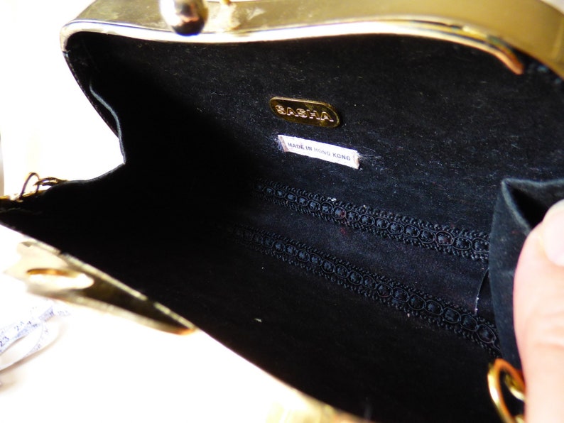 Peut inclure: Pochette en m&eacute;tal dor&eacute; avec un int&eacute;rieur noir et une doublure en tissu noir. La pochette a une petite &eacute;tiquette &agrave; l'int&eacute;rieur qui indique "BABAHA MADE IN HONG KONG".