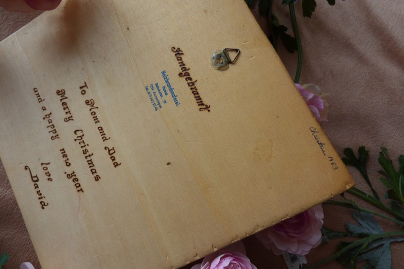 Peut inclure: Une carte de No&euml;l en bois avec une sc&egrave;ne peinte &agrave; la main. Au dos de la carte, un message qui dit "To Mom and Dad Merry Christmas and a happy new year love David" et est sign&eacute; "Christmas 1983".