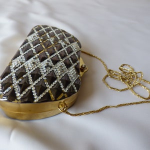 Peut inclure: Un sac de soir&eacute;e noir et or avec un motif en forme de diamant et une bandouli&egrave;re en cha&icirc;ne dor&eacute;e.
