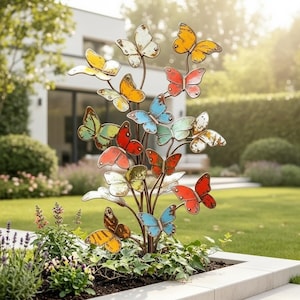 Puede incluir: Una escultura de jardín de metal con múltiples mariposas en varios colores, incluyendo rojo, naranja, amarillo y azul. Las mariposas están unidas a tallos de metal delgados y oscuros que se ramifican desde una base central formando una estructura.