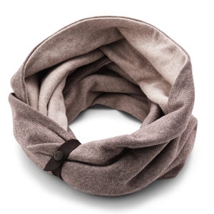 May include: A brown and beige knit infinity scarf with a brown leather strap and a metal button.