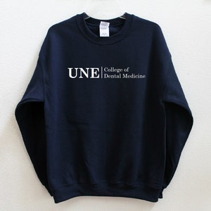 May include: Navy blue sweatshirt with white text that reads "UNE College of Dental Medicine".