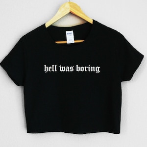 May include: Black cropped t-shirt with the text "hell was boring" in white gothic font.