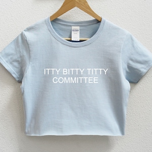 May include: A light blue cropped t-shirt with the text "itty bitty titty committee" printed in white.