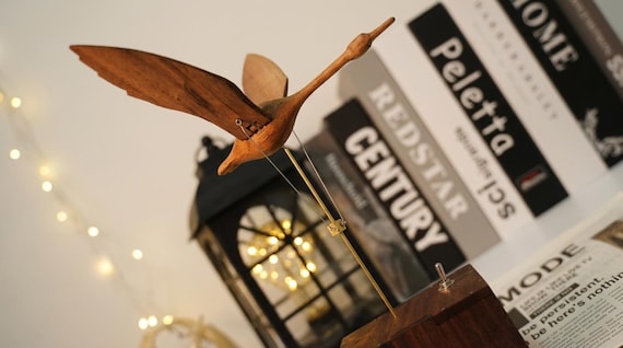 A hand-carved wooden bird automata that actually flaps and moves — the kind of mesmerizing mechanical folk art you'd find in a craftsman's workshop.