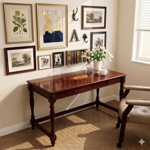 May include: A dark wood desk with a central oval inlay, a single drawer, and turned legs. On the desk sits a white vase with white tulips and a white mug. A beige upholstered chair with wooden arms is positioned next to the desk.