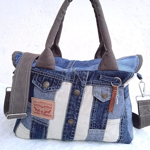 May include: A tote bag constructed from repurposed blue denim and white corduroy fabric. It features a brown Levi Strauss & Co. patch, metal buttons, two brown canvas handles, and a detachable brown canvas shoulder strap with metal clips.