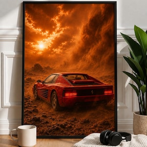 May include: A framed wall art print depicting a red sports car driving across a dusty, rocky landscape under a dramatic orange sunset sky with thick clouds. The car is shown from the rear, featuring horizontal taillights and a black rear grille.