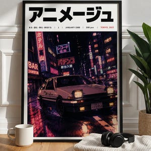 Peut inclure: Une affiche encadrée représentant une voiture blanche et noire avec des phares escamotables sur une rue urbaine humide la nuit, entourée de néons avec du texte japonais. Le haut de l'affiche affiche Animage, janvier 1988, 590 yen et Tokyo, 1923.