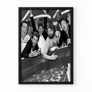 Puede incluir: Una impresión enmarcada en blanco y negro que muestra a un grupo de personas reunidas alrededor de una mesa de dados en un casino. Los individuos se muestran desde el pecho hacia arriba, con expresiones de emoción e intensidad.