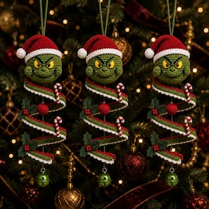 May include: Three identical crochet ornaments featuring a green character head wearing a red and white Santa hat. Below the head is a spiral-shaped green and red ribbon with white trim, decorated with small red berries, holly leaves, and candy canes.