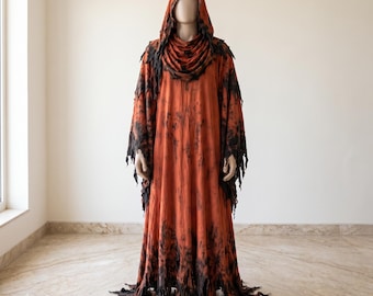 May include: A full-length hooded robe in a burnt orange hue featuring distressed, jagged edges along the hem and wide sleeves. The garment displays a dark, mottled black pattern throughout, with a draped cowl neckline and a pointed hood.