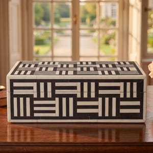 May include: A rectangular storage box featuring a high-contrast black and white geometric pattern. The exterior surface is composed of small, inlaid rectangular tiles arranged in alternating horizontal and vertical striped blocks across the lid and sides.