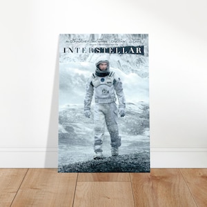 Op de afbeelding: Een filmposter voor Interstellar met een astronaut in een wit ruimtepak die op een besneeuwd, ijzig landschap staat. De titel Interstellar staat bovenaan in dikke zwarte letters, met de namen van de cast en de regisseur erboven vermeld.