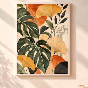 May include: A rectangular wall art print in a white frame featuring a botanical illustration of large dark green monstera leaves, yellow ginkgo leaves, and abstract shapes in burnt orange and black, including thin vertical arched line patterns.