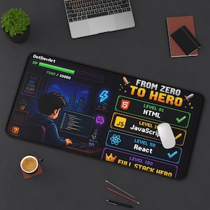 May include: A rectangular desk mat featuring a pixel art design of a person coding at a computer. The graphic includes a progress bar, the text "FROM ZERO TO HERO," and levels for HTML, JavaScript, and React. The mat is black with colourful accents.