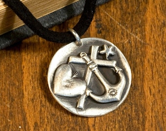 May include: A silver pendant necklace with a heart, cross, and anchor design. The pendant is on a black cord.
