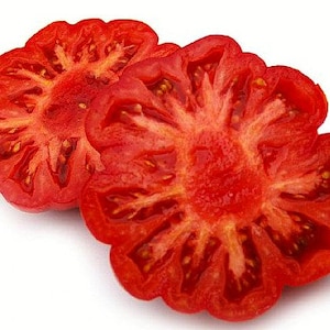 May include: Two red tomato halves, cut across the center, revealing the star-shaped seed cavities and juicy flesh.