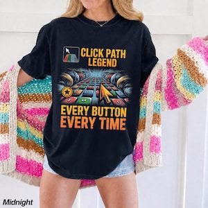 May include: A black short-sleeve t-shirt featuring a graphic print with the text CLICK PATH LEGEND and EVERY BUTTON EVERY TIME. The design includes a computer cursor icon, a grid of colorful square buttons, and a yellow arrow cursor pointer.