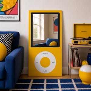 May include: A rectangular yellow mirror designed to resemble a classic digital music player. The mirror features a black rectangular frame at the top and a large white circular control interface at the bottom with the text MENU and playback icons.