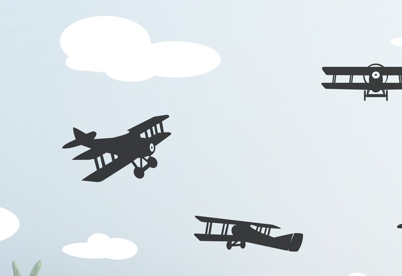 May include: Silhouettes of three black biplanes flying against a light blue background with white clouds.