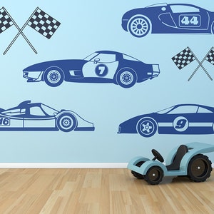 May include: A blue wall with blue racing car decals and checkered flags. The decals include a red race car with the number 44, a blue race car with the number 7, a blue race car with the number 9, and a blue race car with the number 16. There is a toy blue race car in the foreground.