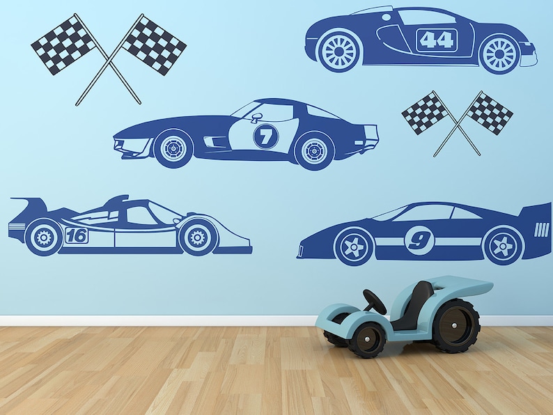 May include: A blue wall with blue racing car decals and checkered flags. The decals include a red race car with the number 44, a blue race car with the number 7, a blue race car with the number 9, and a blue race car with the number 16. There is a toy blue race car in the foreground.