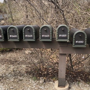 May include: Six black metal mailboxes with white numbers on a wooden post. The numbers on the mailboxes are 6400, 6403, 6405, 6501, and 6550.