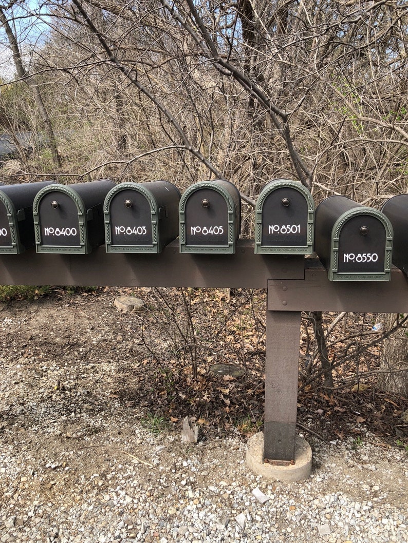 May include: Six black metal mailboxes with white numbers on a wooden post. The numbers on the mailboxes are 6400, 6403, 6405, 6501, and 6550.