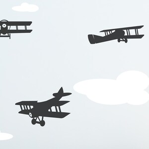 May include: A white background with three black silhouette images of airplanes. The airplanes are flying in different directions. There are also white clouds in the background.