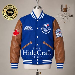 Puede incluir: Una chaqueta universitaria azul con mangas de cuero marrón, que presenta un logotipo blanco de Roots Sporting Goods, un emblema del Toronto Blue Jays Baseball Club, un parche de hoja de arce roja y ribetes acanalados a rayas blancas en el cuello, puños y dobladillo.