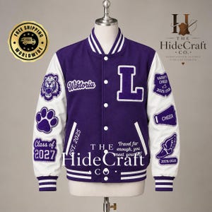 May include: A purple and white varsity jacket featuring a large letter L, the name Wiktoria, and the text Est. 2025. The sleeves are white with purple patches including a lion, a paw print, a megaphone, and a winged shoe with the year 2025/2026.