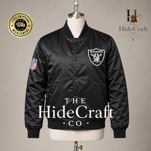 Pode incluir: Uma jaqueta universitária de cetim preto com o logotipo dos Raiders no peito esquerdo e um emblema da NFL na manga direita. A jaqueta possui fecho frontal com botões de pressão, gola canelada e punhos canelados em um acabamento preto liso.