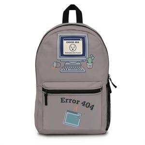 Könnte beinhalten: Ein hellgrauer Rucksack mit einer Grafik eines alten Computermonitors, der ERROR 404 Motivation Not Found anzeigt, sowie einer umgekippten Tasse und einem Kaktus. Die Vordertasche zeigt den Text Error 404 mit einem traurigen Gesicht und Symbol.
