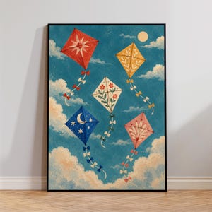Op de afbeelding: Een ingelijste kunstdruk met vijf kleurrijke vliegers in een blauwe lucht met witte wolken en een bleke maan. De vliegers hebben een rood sterontwerp, een geel bladpatroon, een wit bloemmotief, een blauwe halve maan en een roze waaierpatroon.