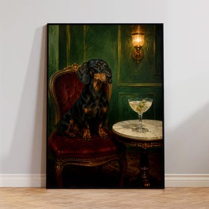 Puede incluir: Una impresión de arte mural enmarcada que muestra a un perro salchicha negro y fuego sentado en una silla tapizada de terciopelo rojo intenso. Junto a la silla hay una pequeña mesa redonda de mármol con una copa de martini y aceitunas.