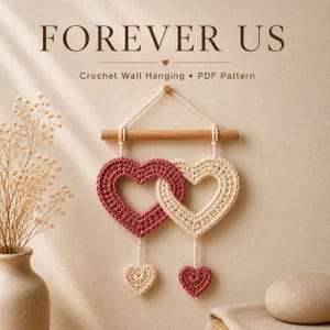 May include: A crochet wall hanging featuring two interlocking hearts, one dark pink and one cream, suspended from a wooden dowel. Below each large heart hangs a smaller matching heart. The text FOREVER US Crochet Wall Hanging PDF Pattern is visible.