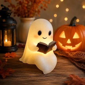 May include: A glowing, off-white ghost figurine with a smooth, rounded shape, black eyes, and pink cheeks, holding a small, open dark book. The ghost emits a soft, warm light from within, creating a gentle illumination on its surface.