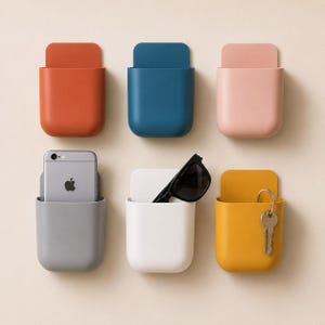 May include: Six wall-mounted storage pockets in orange, blue, light pink, gray, white, and yellow. The gray pocket holds a silver smartphone, the white pocket contains black sunglasses, and the yellow pocket holds a silver metal key on a ring.