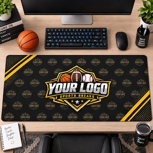 May include: A rectangular black desk mat featuring a repeating pattern of a sports logo. The central graphic displays a basketball, football, and baseball above the text YOUR LOGO SPORTS BREAKS in white and gold, accented by yellow diagonal stripes.