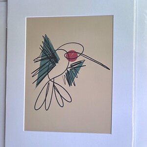 May include: Abstract art print of a hummingbird in a white mat. The hummingbird is depicted with black line art, teal accents, and a red circle. The background is a light tan color.